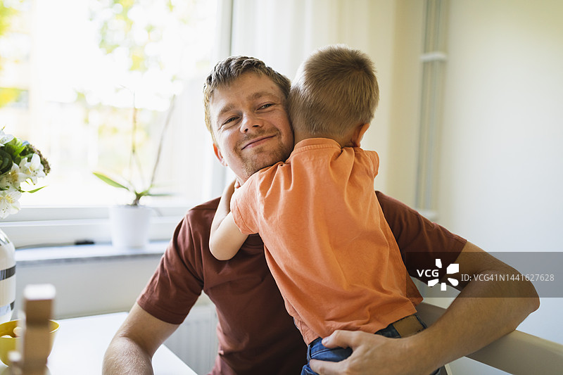 男孩在家中拥抱微笑的父亲图片素材