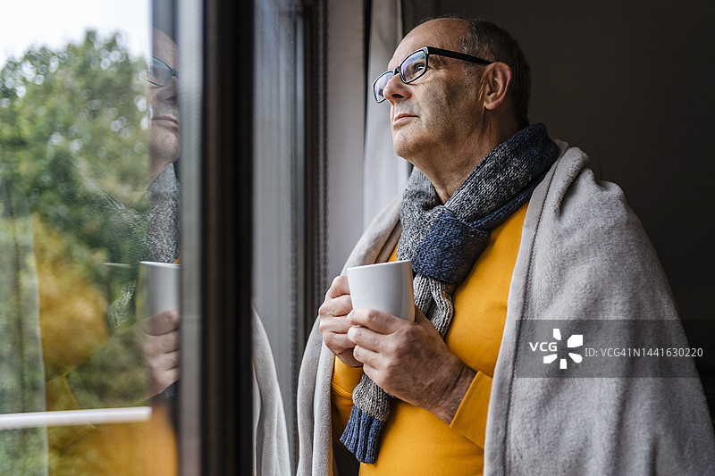 思考的男人在家中喝茶，望向窗外图片素材