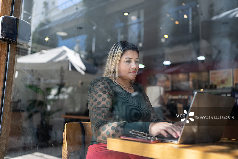 中年女人在咖啡店里使用笔记本电脑图片素材