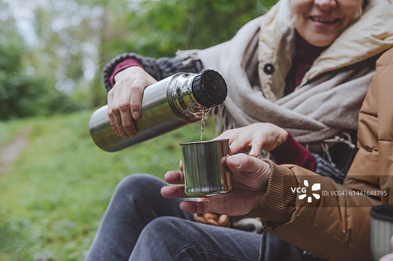 女人在森林里给男人倒水从保温瓶里图片素材