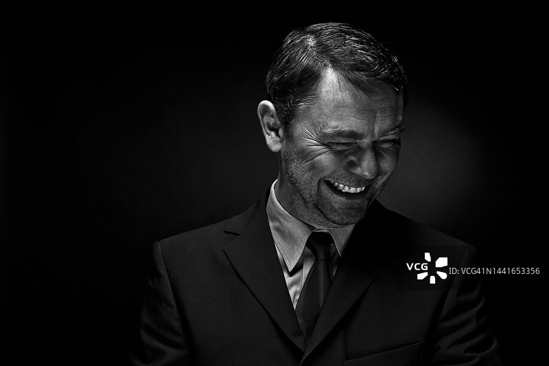 中年男人对着黑色背景微笑图片素材