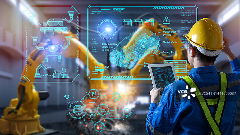 工程师在工厂控制机器人自动臂焊接电动汽车图片素材