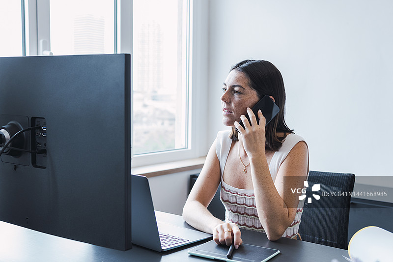 年轻女商人在办公室通过智能手机交谈图片素材