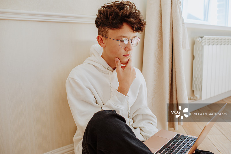 男孩双手托腮在笔记本电脑上进行在线学习图片素材