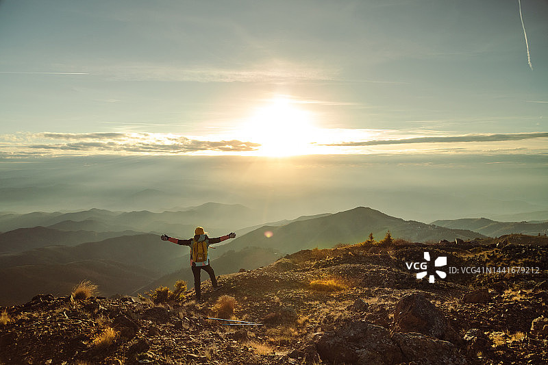 女登山者在山顶伸展双臂图片素材