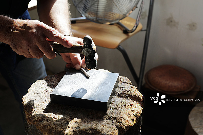 珠宝商在工作室里锤击金属制作珠宝图片素材