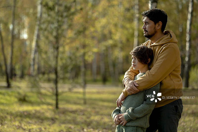 父亲在公园里从后面拥抱男孩图片素材