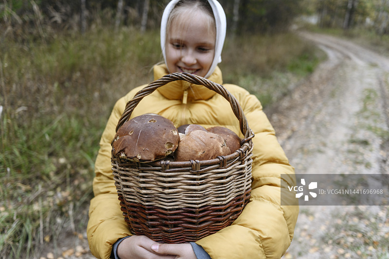 微笑女孩在人行道上手提一篮蘑菇图片素材