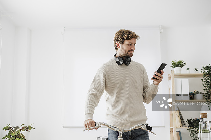 在工作场所使用智能手机的骑自行车的商人图片素材