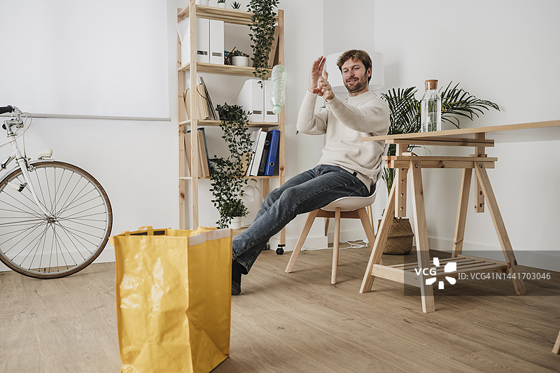 商人在工作场所将塑料瓶扔进黄色垃圾袋图片素材