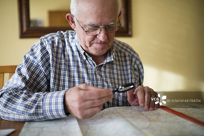 年长的男人用放大镜看地图图片素材