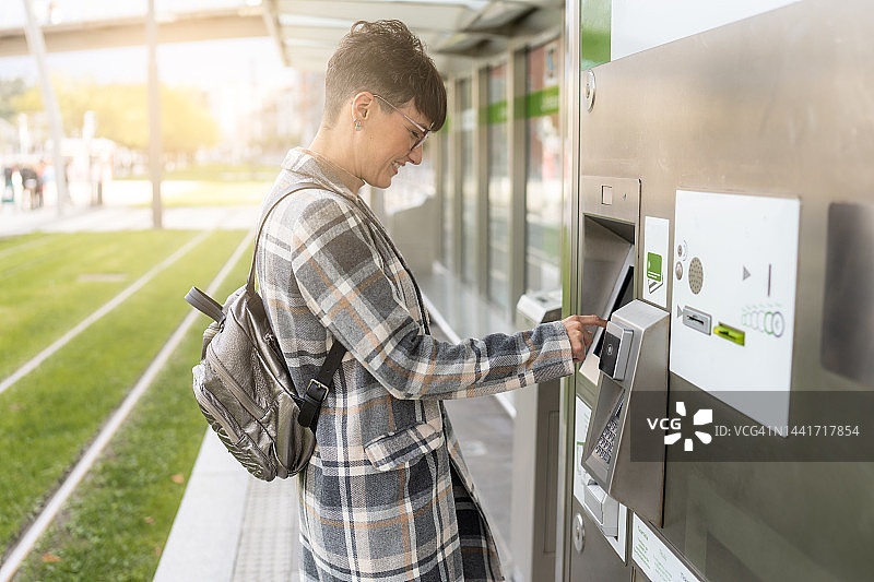 女人在城市公共交通上取电车票图片素材