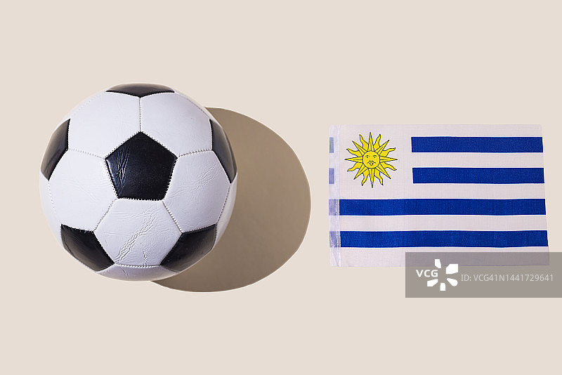 乌拉圭国旗旁边的复古足球，白色、蓝色条纹和一个太阳，在柔和的背景上。足球、世界杯、体育、比赛和世界冠军概念图片素材