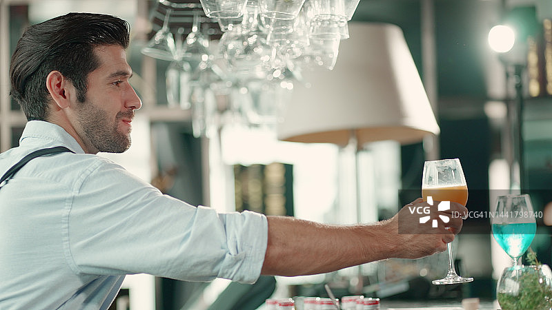 年轻的调酒师系着围裙，准备在聚会、酒吧或餐厅调制饮品，人们来这里闲逛、旅行、聊天、玩乐和放松，一起喝酒。人们的生活方式。图片素材