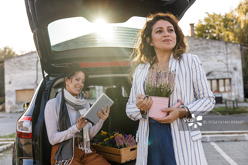 年轻女人坐在后备箱里，准备送货时使用平板电脑图片素材