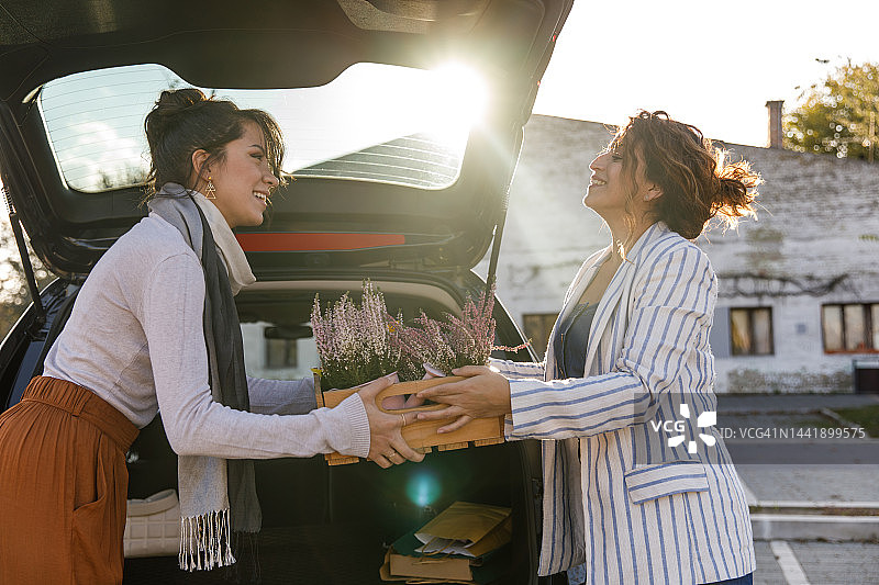 花艺师将鲜花交给顾客，以便装载到后备箱图片素材