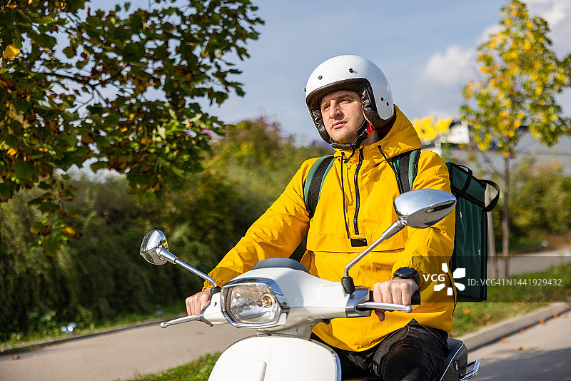 配送员骑着踏板车在城市中送货图片素材