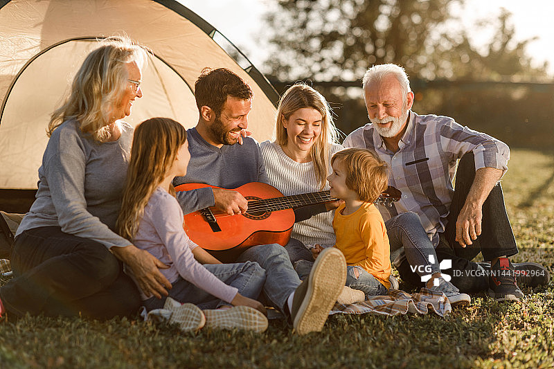 快乐的大家庭在野外露营时享受吉他音乐图片素材