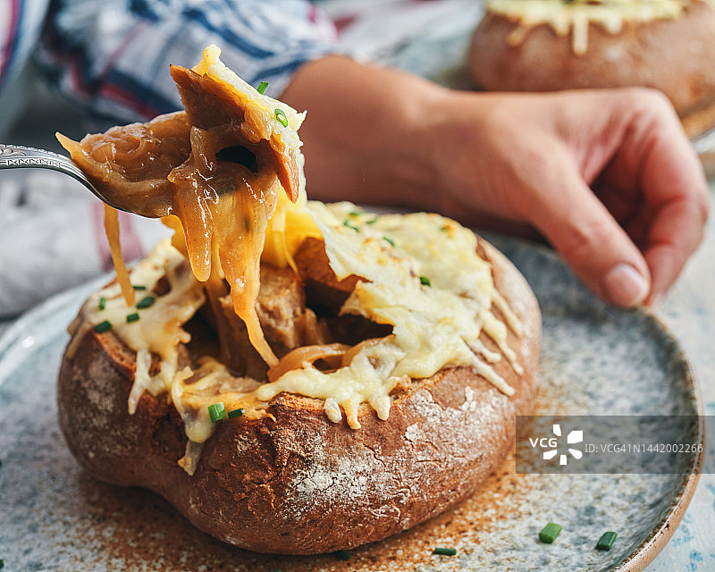 吃法式洋葱面包碗配格鲁耶尔奶酪图片素材