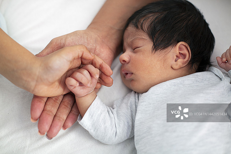 家庭与新生婴儿的手，姐妹和母亲的呵护图片素材