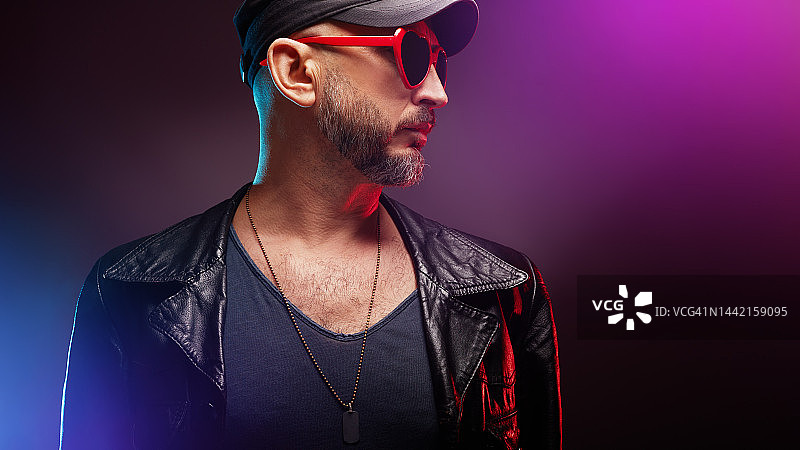 时尚英俊的男人在霓虹灯下戴着红色心形太阳镜图片素材