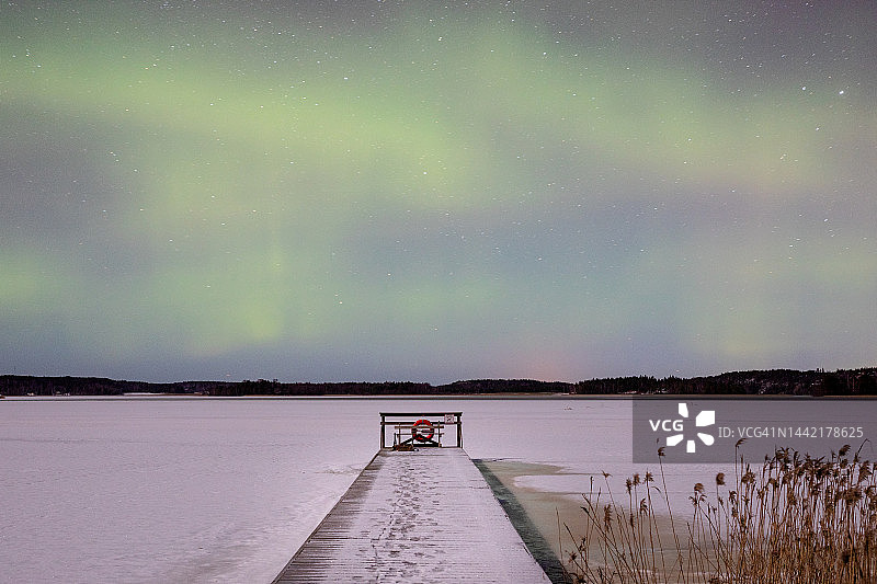 奥兰群岛戈德比公共海滩码头，冰雪覆盖的月光下北极光图片素材