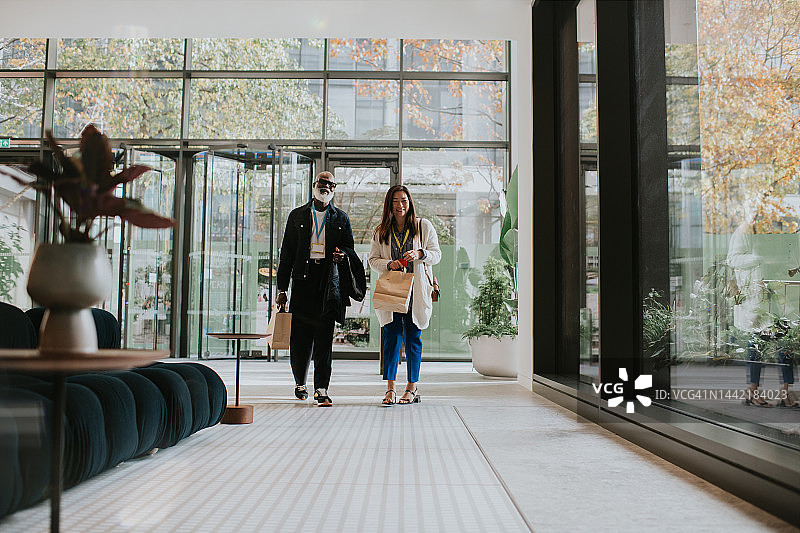 两个人走进明亮商业空间拎纸袋图片素材