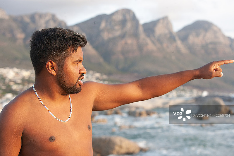 赤膊年轻男子指向水面上的地平线图片素材