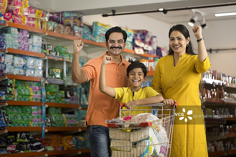 快乐的一家人在超市里举起紧握的拳头图片素材