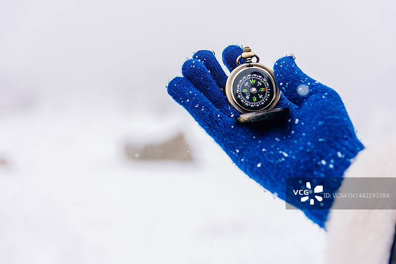手戴羊毛手套在雪地里拿着指南针图片素材