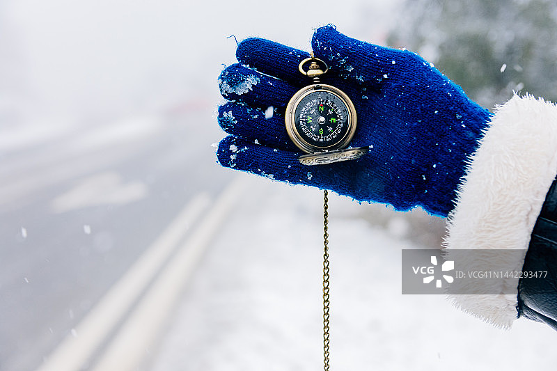 手持金色指南针，指向雪景道路图片素材