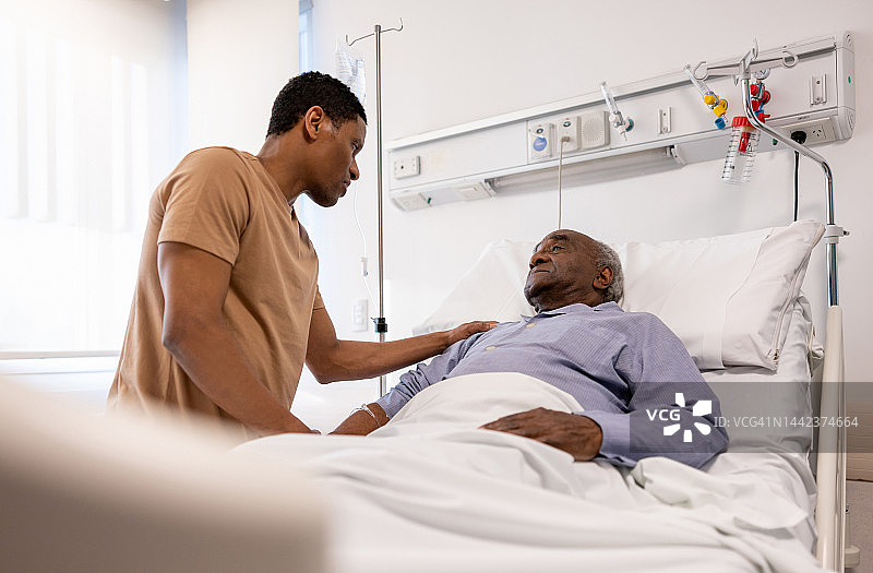 儿子在医院里躺在病床上和父亲说话图片素材