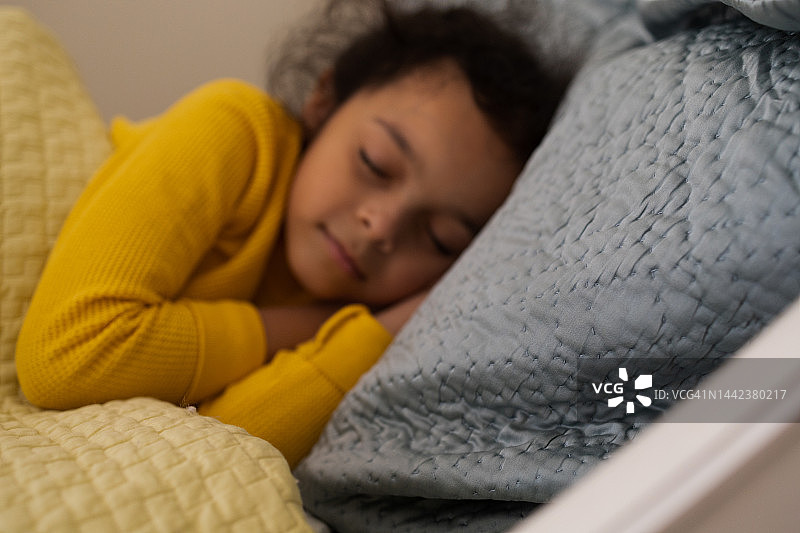 在加重毯下熟睡的年轻混血女孩图片素材