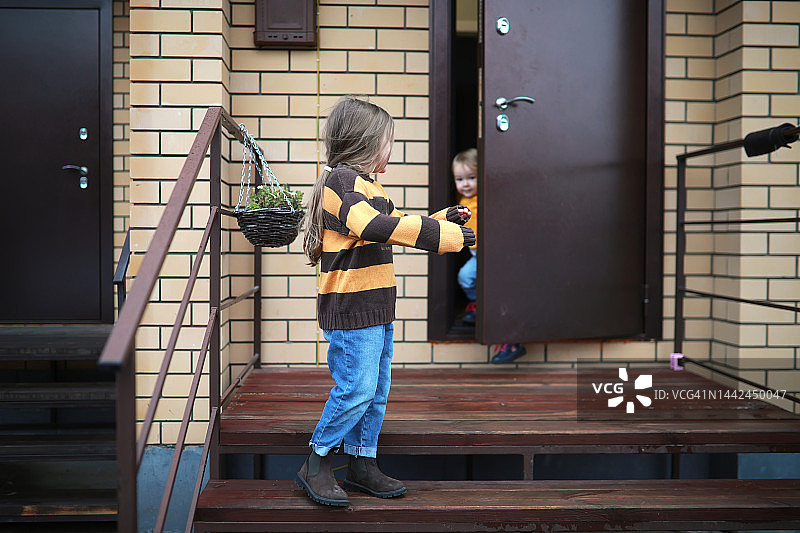 穿毛衣的孩子们离开门廊上的房子。砖砌联排别墅。图片素材
