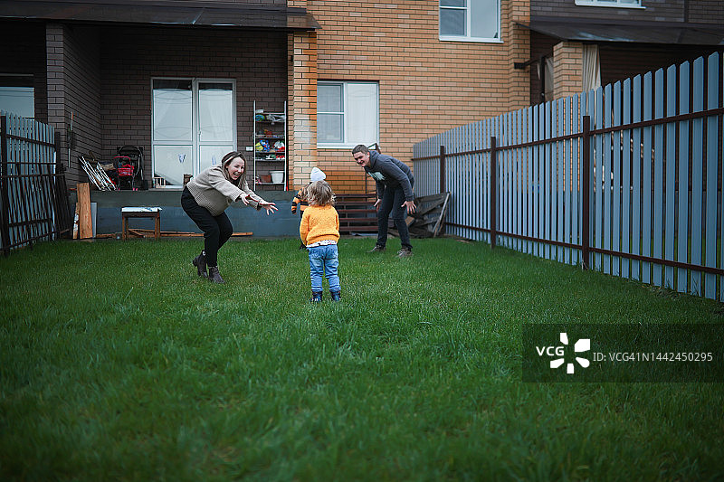 穿毛衣的孩子和父母在后院草坪上奔跑图片素材