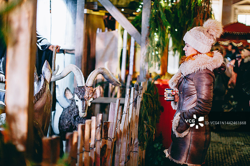 穿着暖和衣服在圣诞市场看装饰摊位的女人图片素材
