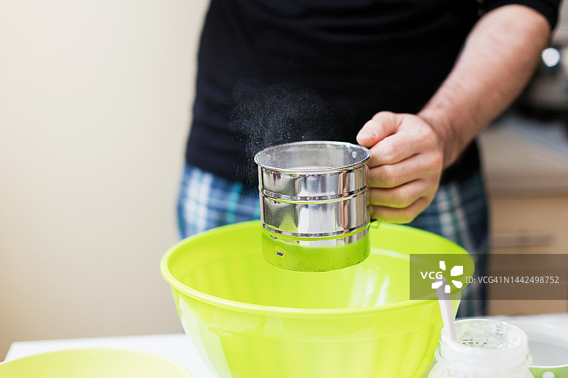 在厨房筛面粉的白人男子图片素材