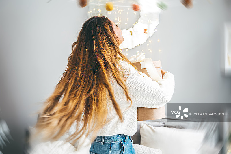 女子手拿礼物，在圣诞装饰前摇曳图片素材
