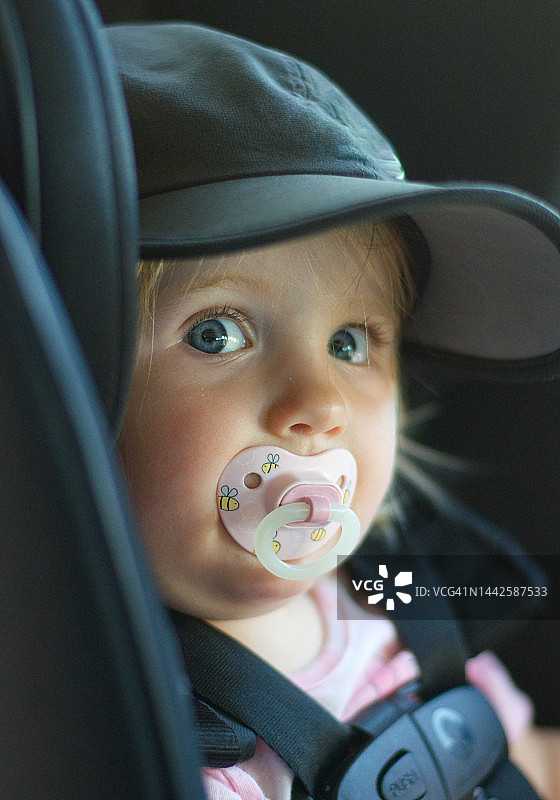 坐在汽车安全座椅上含着奶嘴的婴儿图片素材