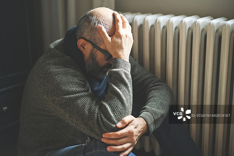 中年男人在房间里用暖气取暖图片素材