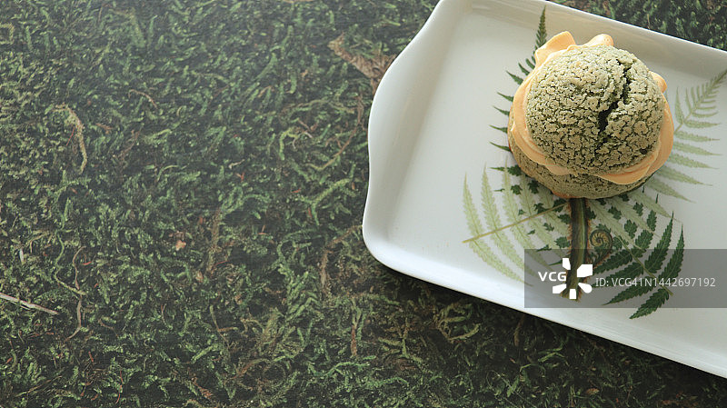 一块抹茶泡芙放在银蕨背景的托盘上图片素材