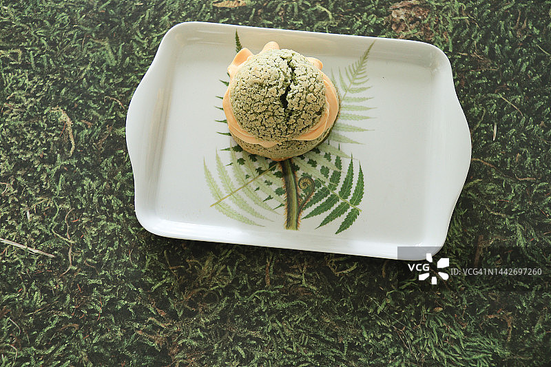 一块抹茶泡芙放在银蕨背景的托盘上图片素材