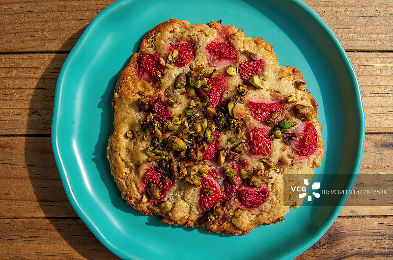 木桌上盘子里的草莓开心果烤饼图片素材