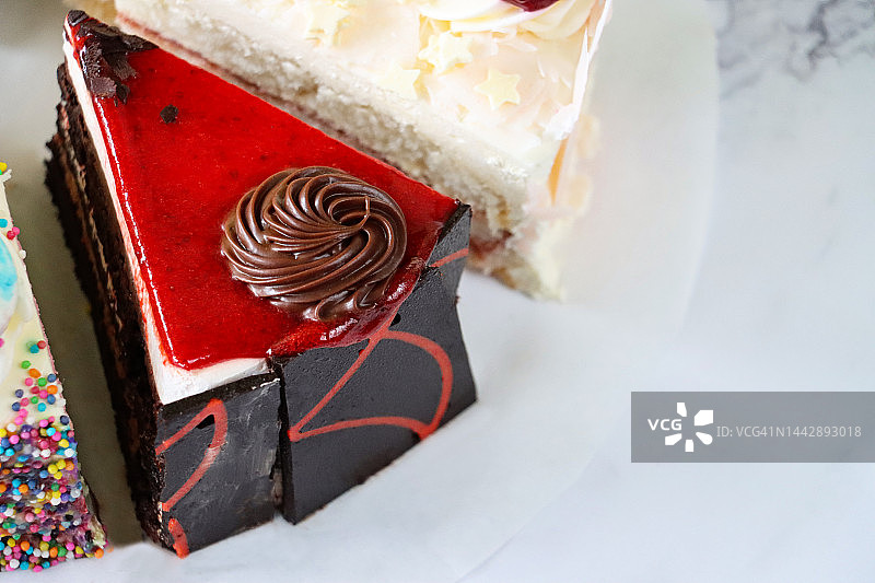 羊皮纸上的切片蛋糕品种特写：巧克力樱桃蛋糕、彩虹蛋糕、天使蛋糕图片素材