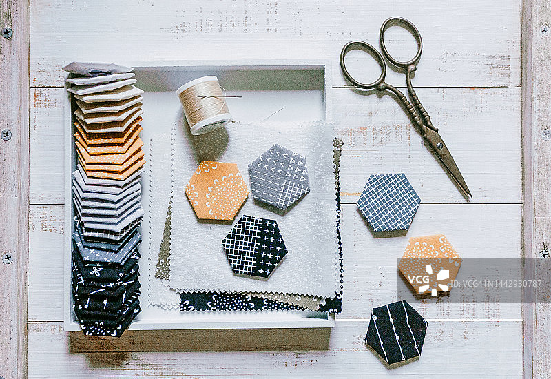 绗缝缝纫配件，拼布六边形块状图案。拼布灰色黄色块状绗缝，缝纫配件，木质背景上的面料。平铺图片素材