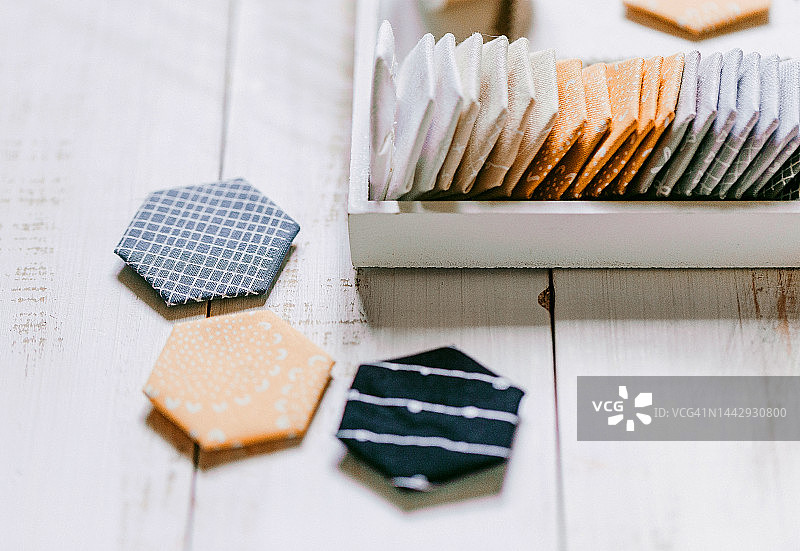 绗缝缝纫配件，拼布六边形块状图案。拼布灰色黄色块状绗缝，缝纫配件，木质背景上的面料。平铺图片素材