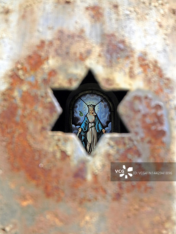 巴黎，透过风化金属门上的星星切口看到的彩色玻璃窗上的圣母玛利亚图片素材