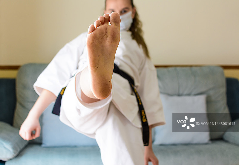 戴口罩在家练空手道的金发女孩图片素材