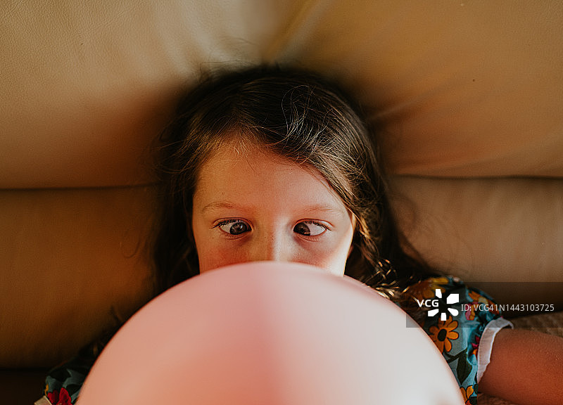 一个孩子对刚吹大的气球的尺寸感到不知所措的幽默形象图片素材