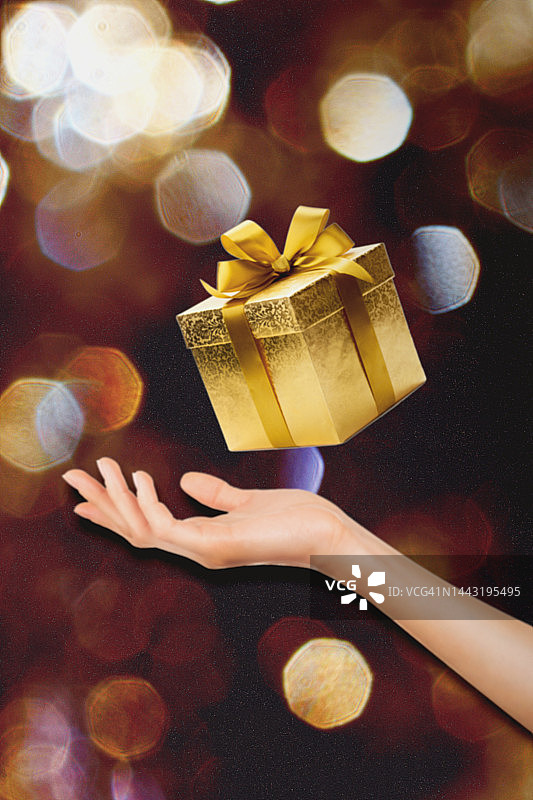 手中拿着金色礼物，背景虚化图片素材